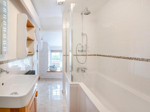 a white bathroom with a tub and a sink at 1 bed property in Kidwelly 43409 in Kidwelly