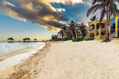 a beach with a building and a pier at The Oasis Tulum Luxury Front Beach Villa 8 Rooms in Tankah