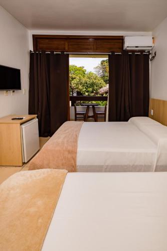 a hotel room with two beds and a window at Casa Blanca Park Hotel in Porto Seguro