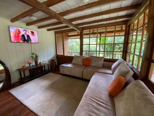 a living room with a couch and a tv at Wooden House Mindo - Casa de Las Nevadas in Mindo