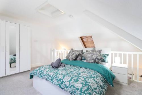 a white bedroom with a bed with green and gray pillows at Stylish Retreat in Nuneaton Centre with Sofa Bed, Garden and Super Fast Wi-Fi in Nuneaton