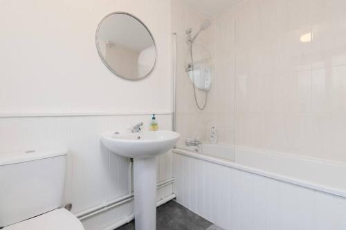 a white bathroom with a sink and a mirror at Stylish Retreat in Nuneaton Centre with Sofa Bed, Garden and Super Fast Wi-Fi in Nuneaton