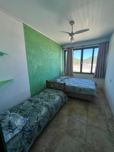 a bedroom with two beds and a ceiling fan at Pousada do Luz in Imbituba