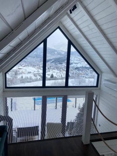 a large window in a room with a mountain view at Under Sky Slavske - Котеджі з Теплим басейном ,чаном-джакузі, панорамною ванною та PlayStation 5 in Slavske