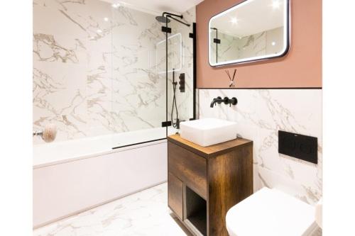 ein Badezimmer mit einem Waschbecken, einer Badewanne und einem Spiegel in der Unterkunft Victorian Apartment With Sea Views By Adliv Host in Ramsgate