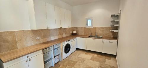 eine Küche mit weißen Schränken, einer Waschmaschine und einem Trockner in der Unterkunft Villa de standing Les Amandiers, vue mer & piscine in Propriano