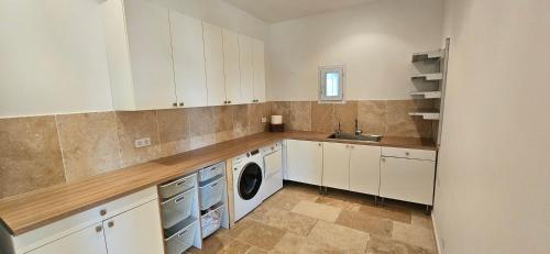 una cucina con mobili bianchi, lavatrice e asciugatrice di Villa de standing Les Amandiers, vue mer & piscine a Propriano