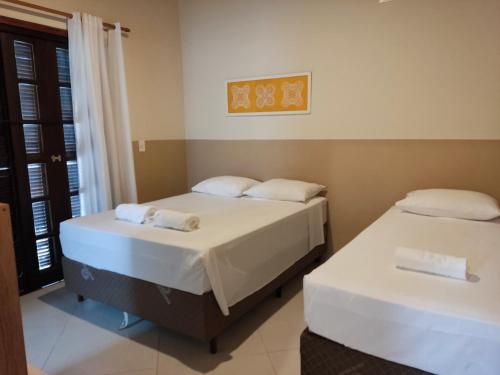 dwa łóżka w pokoju z oknem w obiekcie Casa Azul Perequê w mieście Ilhabela