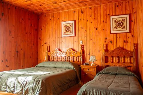 2 camas en una habitación con paredes de madera en Pousada Vale Verde, en Campos do Jordão