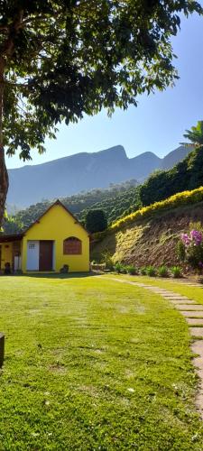 een geel huis in het midden van een grasveld bij chale 2 canto das montanhas in Caparaó Velho