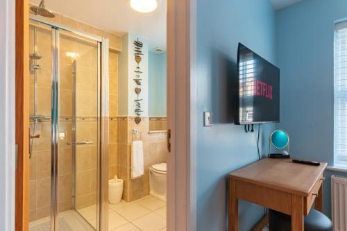 a bathroom with a shower and a desk and a television at Beautiful Margate Coastal Home With Parking in Margate