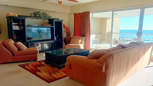 een woonkamer met een bank en een tv bij Encanto Living 304 Spacious, 2 Bedroom Ocean View!! in Playa Encanto