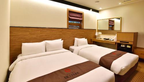 a hotel room with two beds and a mirror at Hotel Skypark Myeongdong 1 in Seoul