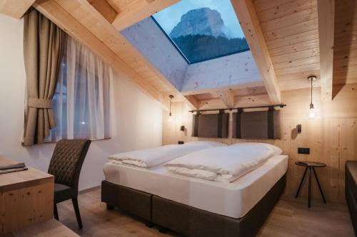 a bedroom with a large bed with a skylight at Vila Altonn in Colfosco