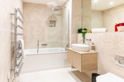 a bathroom with a tub and a toilet and a sink at Luxury Ocean & North Foreland Golf View Escape in Broadstairs