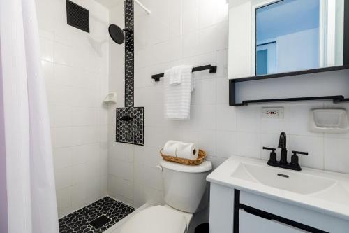 a white bathroom with a toilet and a sink at Fortuna Paradise in Luquillo