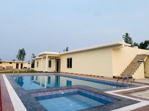 a house with a swimming pool in front of it at New Corbett Hotel and Resort in Belparāo