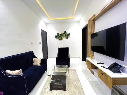 sala de estar con sofá azul y TV en Riviera Hotel, Apartments & Resorts, en Lekki