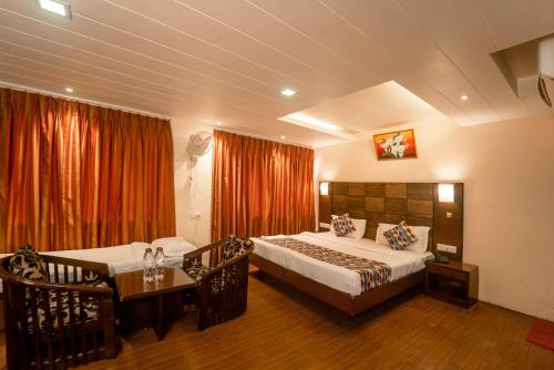 Vatika Inn Hotel City Center في أودايبور: غرفة نوم بسريرين وطاولة ونافذة