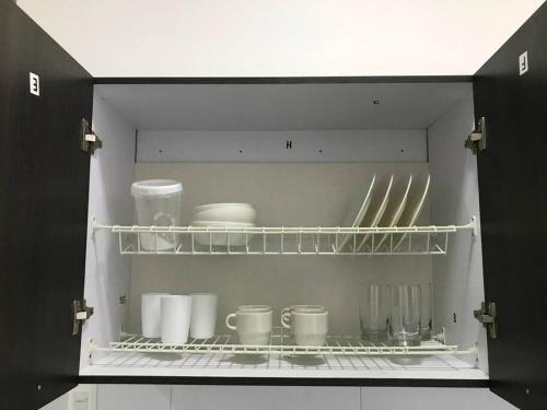 an open cabinet with cups and dishes in it at Hermoso apto en Barrancabermeja in Barrancabermeja