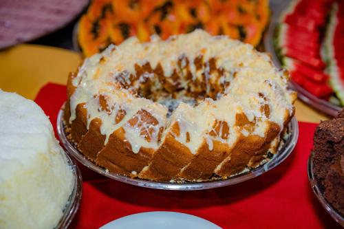 a cake with white frosting on a table with other cakes at Hotel Casa Blanca Porto Seguro in Porto Seguro
