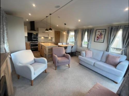a living room with a couch and two chairs and a kitchen at 2-6 guests Holiday Chalet in Durdle Door in West Lulworth