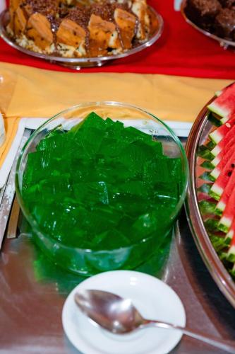 a green glass bowl with a spoon on a table at Hotel Casa Blanca Porto Seguro in Porto Seguro