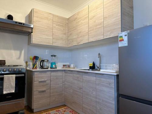 a kitchen with wooden cabinets and a refrigerator at Tú Casa en Puerto Natales in Puerto Natales