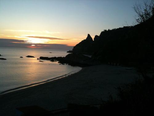 a sunset on a beach with the sun setting at Gullo Capo Vaticano in Ricadi