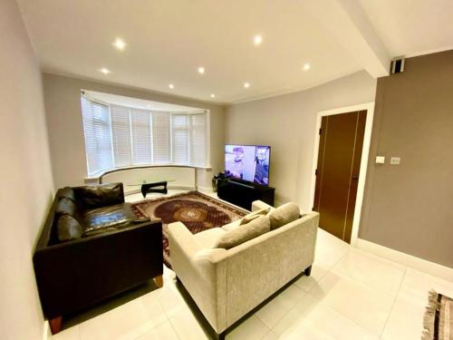 a living room with a couch and a tv at Luxury 5 bedroom house with Private car park in London in Hendon