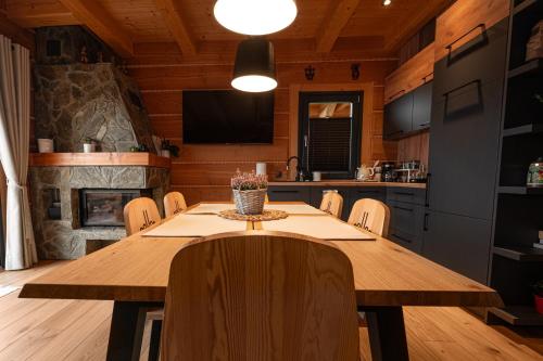 a dining room with a wooden table and a fireplace at Domek drewniany w górach Jacuzzi & Balia - Osada Chełm in Stróża