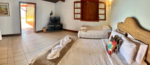 a living room with a bed and a tv at OYO Deck Da Villa Pousada Hotel in Picinguaba