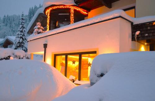 a house covered in snow in front of a building at Pension Zillertal in Gerlos