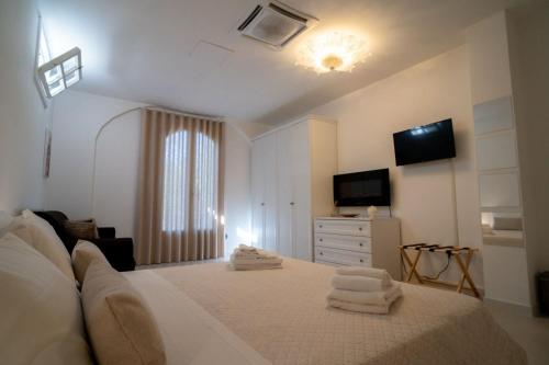 Un dormitorio blanco con una cama con toallas. en Lamapulia, en Torre a Mare