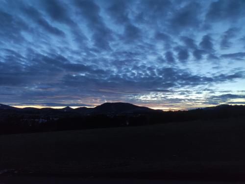 Un cielo nublado sobre un campo con montañas al fondo. en Moon Apartman Zlatibor, en Zlatibor
