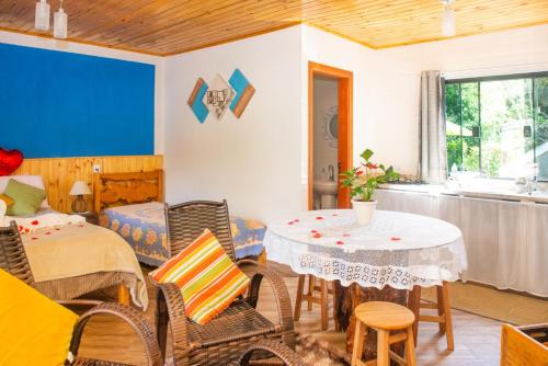 ein Wohnzimmer mit einem Tisch und Stühlen in der Unterkunft Chalé Lírio Cachoeira do Vale in Monte Verde