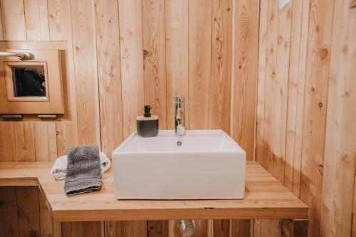 La salle de bains est pourvue d'un lavabo blanc sur un comptoir en bois. dans l'établissement Koča Bistra - Velika planina, à Stahovica