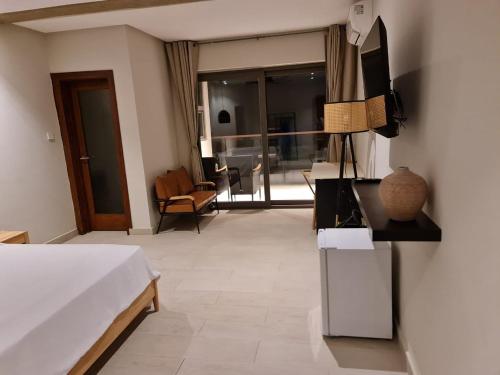 a bedroom with a bed and a television and a living room at Serenity Terraces Beach, Hotel - Kokrobite in Kokrobite