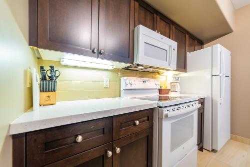 - une cuisine avec des appareils blancs et des armoires en bois dans l'établissement Horseshoe Valley Suites - The Aurora, à Shanty Bay