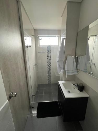uma casa de banho com um chuveiro, um lavatório e um espelho. em Luxor apartamentos em Medellín