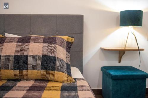 a bed with a plaid pillow and a green stool at MY HOME in Áno Lekhónia