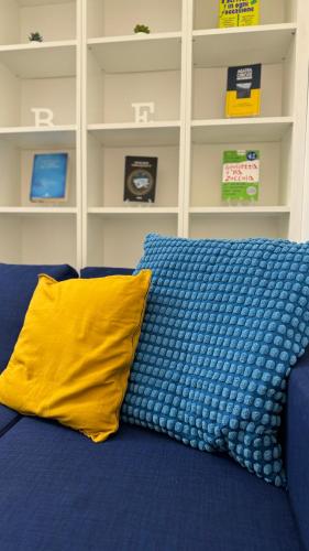 a blue couch with a yellow pillow on it at suite cubè al centro storico vicino la scuola Vespucci con parcheggio su richiesta in Frattamaggiore