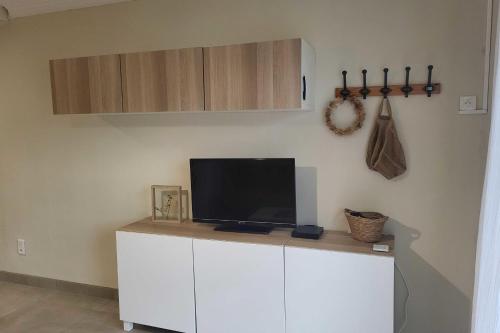 - une télévision au-dessus d'un meuble blanc dans l'établissement Apartment with garden - sea view, à Palavas-les-Flots
