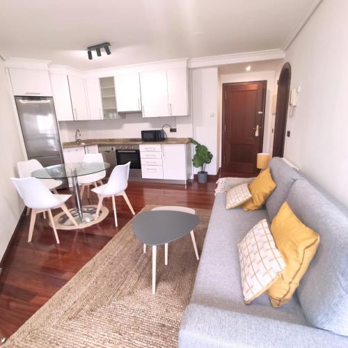 een woonkamer met een bank en een tafel en een keuken bij Espectacular Apartamento Olívico con Parking in Vigo