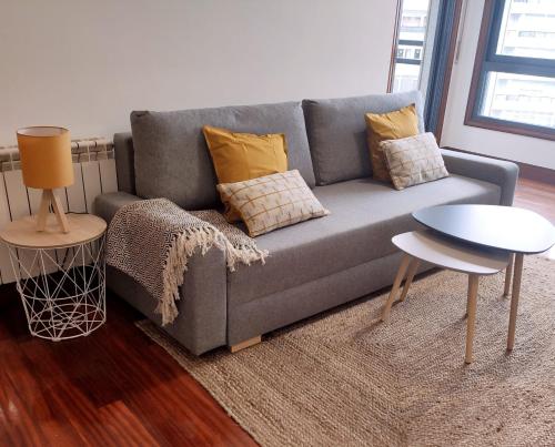 een woonkamer met een grijze bank en een tafel bij Espectacular Apartamento Olívico con Parking in Vigo