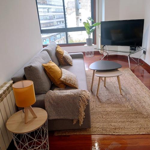 een woonkamer met een bank en een tv bij Espectacular Apartamento Olívico con Parking in Vigo