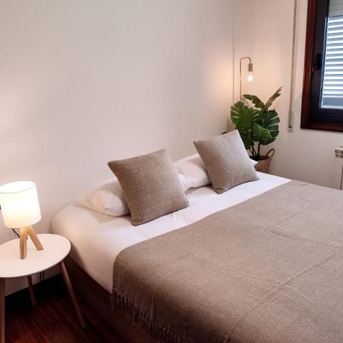 een slaapkamer met een bed en een tafel met een lamp bij Espectacular Apartamento Olívico con Parking in Vigo
