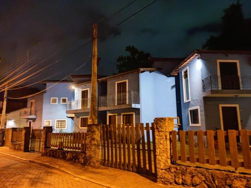 une maison avec une clôture devant elle la nuit dans l'établissement Casa Azul Perequê, à Ilhabela