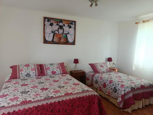 a bedroom with two beds and a mirror on the wall at cabañas Te Pito Kura in Hanga Roa