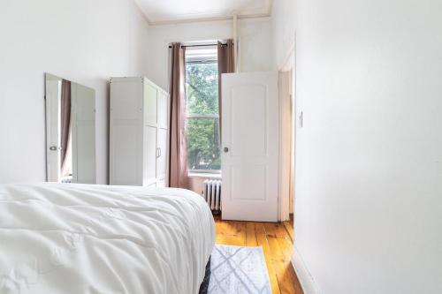 a white bedroom with a bed and a window at Apartment 1411: Fort Greene in Brooklyn